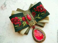 a close up of a bow tie with flowers on it and a brooche hanging from the side