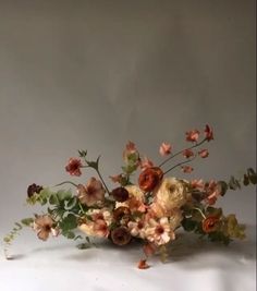 an arrangement of flowers on a white surface