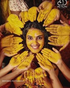 a woman with yellow paint on her face is surrounded by hands in the shape of a sunflower