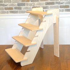 a wooden stair case sitting on top of a hard wood floor next to a brick wall