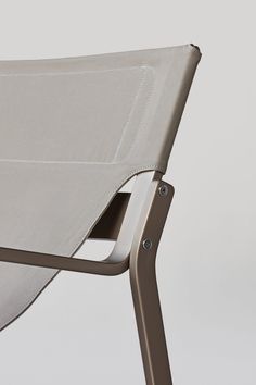 the back side of a folding chair with white fabric and metal frame, viewed from below