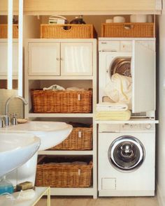 a washer and dryer in a small room with baskets on the shelves next to it