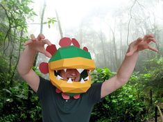 a man wearing a paper mask in the middle of a forest with his hands up