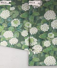 two green and white wallpapers with flowers on them, one is rolled up to the side