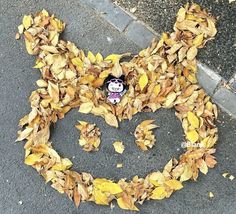 a mickey mouse head made out of leaves on the ground with a sticker in it's mouth