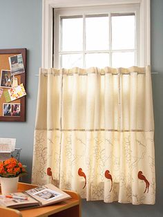 a room with a table, window and pictures hanging on the wall above it's windowsill