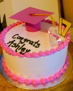 a white cake with pink frosting and a graduation cap on top