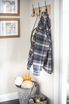 a coat rack is hanging on the wall next to two baskets filled with fruit and vegetables