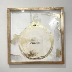 a chanel bottle in a gold frame on the wall