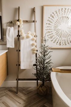 a bathroom with a ladder, towel rack and christmas tree in the bathtub area