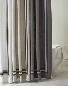 a white toilet sitting next to a gray and black shower curtain on top of a bath tub