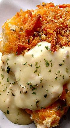 a white plate topped with mashed potatoes covered in gravy and parmesan cheese