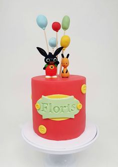 there is a red cake decorated with balloons and an animal figure on the top tier