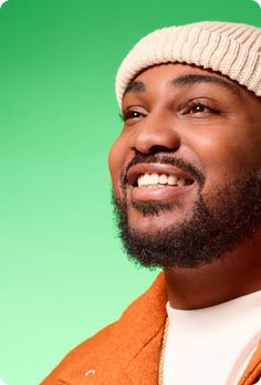 a man with a beard wearing an orange jacket and a white knitted beanie