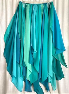 a skirt hanging on the wall in front of a white curtain with blue and green colors