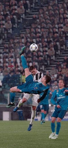 two men are playing soccer in front of an audience while one man jumps up to head the ball