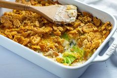 a casserole dish filled with chicken and vegetables next to a wooden spatula