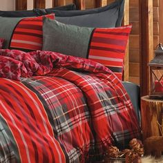 a bed with red and black plaid comforter, pillows and blankets on top of it