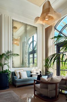 a living room filled with lots of furniture and large windows next to a tall potted plant