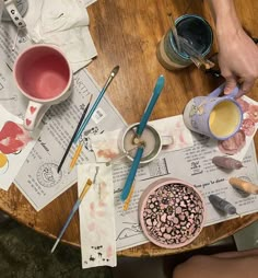 someone is painting on the table with paint and other crafting supplies around it,