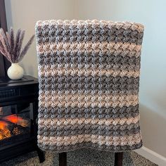 a crocheted blanket sitting on top of a chair next to a fire place