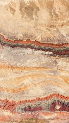 an aerial view of mountains and valleys in brown, green, yellow and orange colors