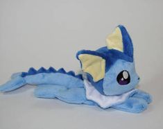 a blue stuffed dragon laying on its side with it's eyes open and tongue out