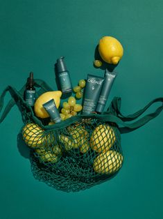 a mesh bag filled with different types of skin care products next to lemons and grapes