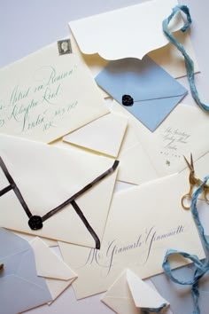 an assortment of envelopes with blue ribbon tied around them and some writing on them