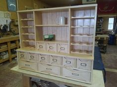 a wooden cabinet with drawers and shelves in a room filled with workbench tools