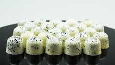 black and white candies with sprinkles on them sitting on a plate