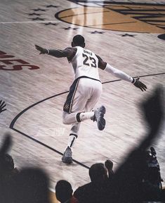 a basketball player dribbling the ball during a game with fans in the stands