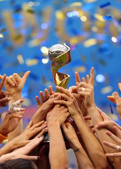 a group of people holding up a trophy in the air with their hands raised to it