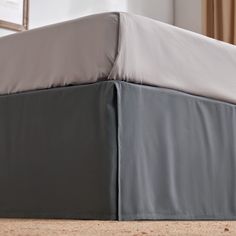 an image of a bed that is made with grey sheets and white sheets on it