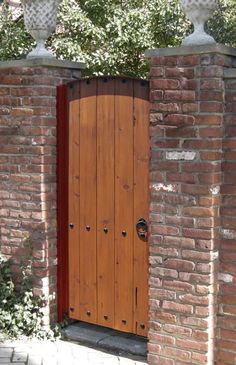 an open wooden door is in between two brick pillars on the side of a building