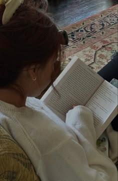 a woman sitting on a couch reading a book