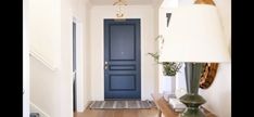 a blue door is in the hallway next to a lamp and table with two lamps on it