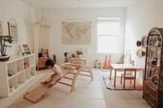 a child playing in a play room with furniture and decor on the walls, including bookshelves