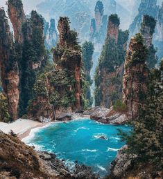 the blue water is surrounded by rocky cliffs and trees on either side of the beach