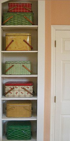 an open bookcase with baskets and boxes on the bottom shelf, in front of a door