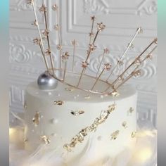 a white cake with gold stars and sparkles on it's icing decoration