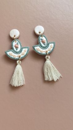 two pairs of earrings with tassels and beads hanging from the side on a pink background