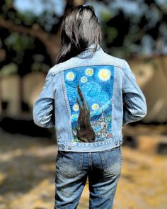 the back of a woman's jean jacket with an image of a cat on it