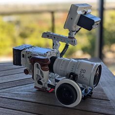 a camera sitting on top of a wooden table next to a video camera with a lens attached