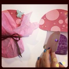 a person is cutting paper with scissors on a table next to some decorations and cards