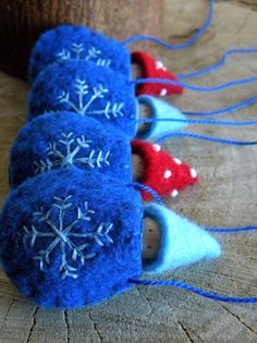 three felt snowflakes are sitting on a piece of wood