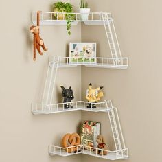 three white shelves with stuffed animals, toys and books on them against a beige wall