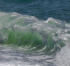 a person riding a surfboard on top of a wave in the ocean with green and white colors