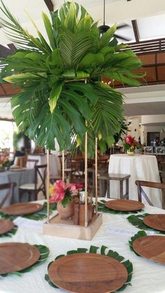 a table with plates and palm tree on it in a room that has tables set up for an event