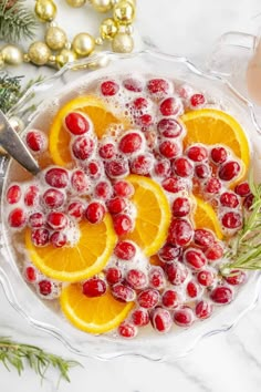 oranges and cranberries are in a bowl with ice